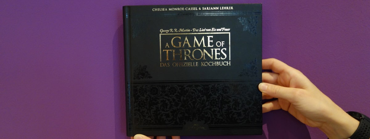 Schwarzes Cover des Game-of-Thrones-Kochbuchs auf lila Hintergrund