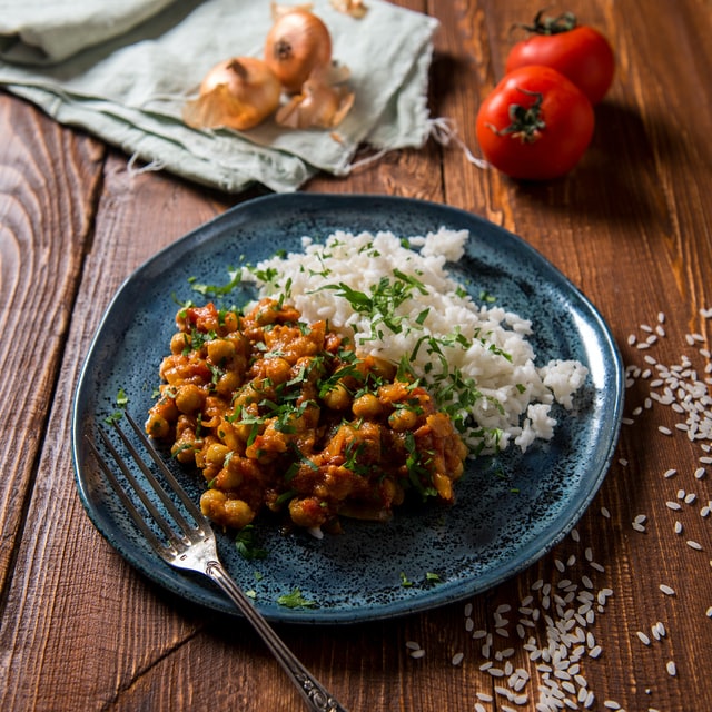 Kichererbsen-Curry mit Reis auf einem blauen Teller