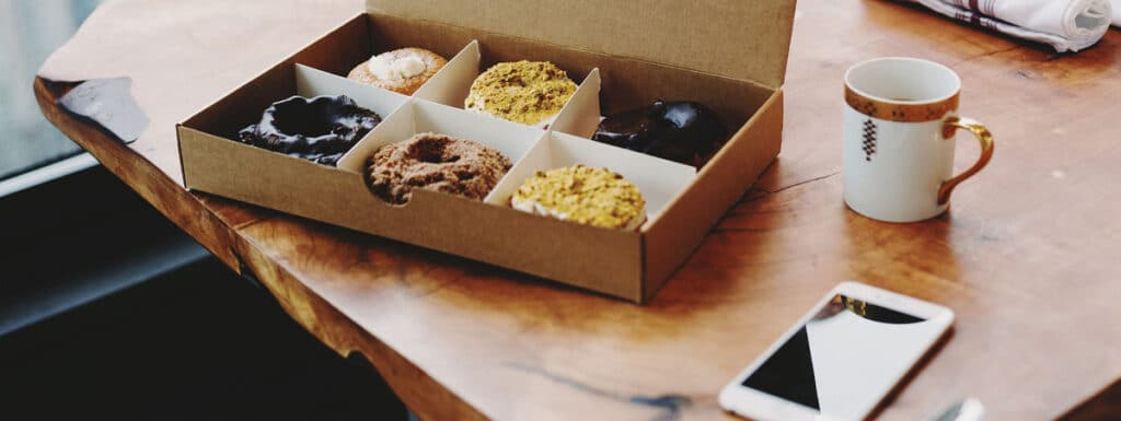 Handy und Box mit Donuts auf Tisch