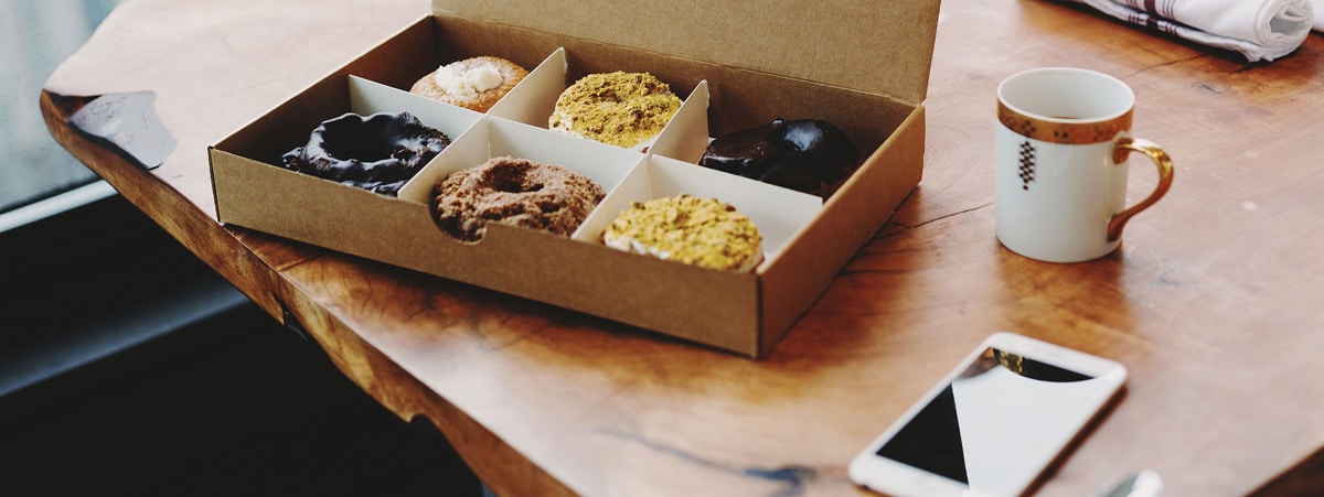 Handy und Box mit Donuts auf Tisch