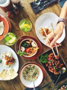 Asiatisches Essen auf Tisch, Hand mit Stäbchen