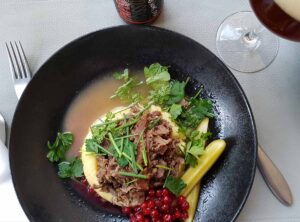 Küche Finnlands: Fleisch, viele Kräuter, Essiggurken, Kartoffelpüree und Preiselbeeren auf einem Teller serviert.