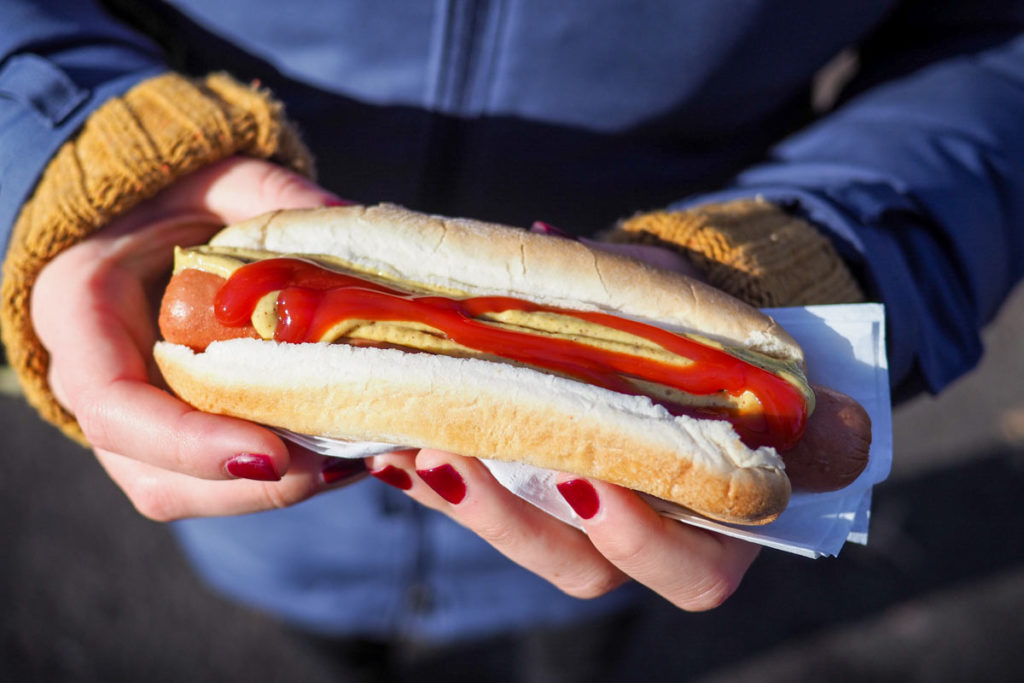 Hände halten einen Hot Dog