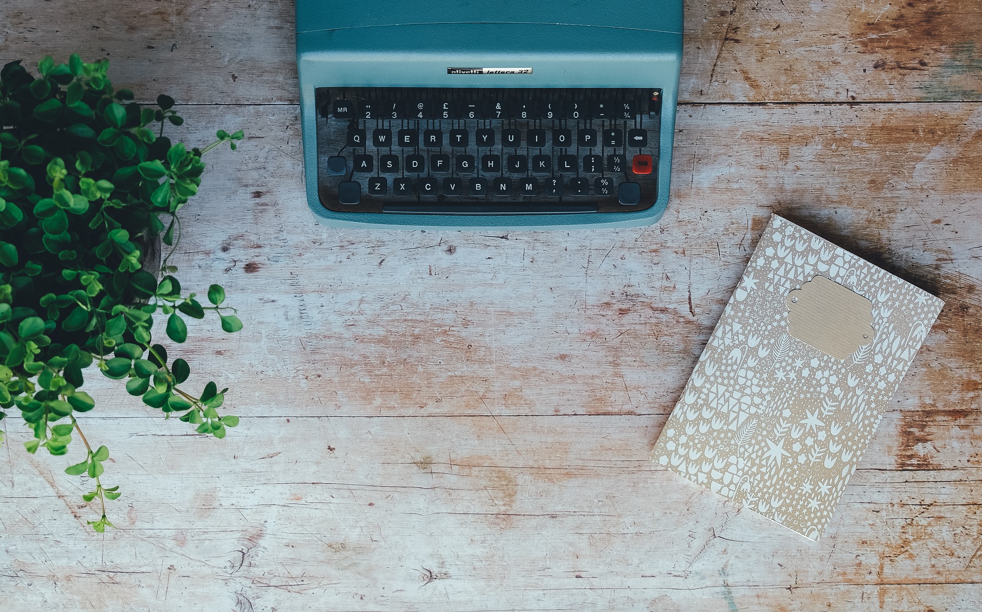 Schreibmaschine mit Blume und Notizbuch